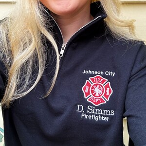 May include: Black mock neck sweatshirt with a white embroidered firefighter logo and the text "Johnson City Fire Dept. D. Simms Firefighter".