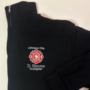 May include: Black quarter-zip sweatshirt with a white embroidered logo that says "Johnson City Fire Dept." and "D. Simms Firefighter".