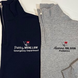May include: Two black and gray quarter-zip sweatshirts with embroidered logos. The black sweatshirt has the text "Patty, MSW, LSW Emergency Department" and the gray sweatshirt has the text "Alanna RN, BSN Pediatrics".