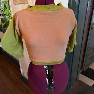 Op de afbeelding: Een shirt met korte mouwen, in twee kleuren, in groen en bruin. Het shirt heeft een hoge halslijn en een aansluitende pasvorm.