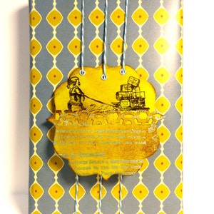 May include: A blue and yellow patterned gift wrap with a yellow tag attached. The tag features a vintage illustration of a person pulling a sled full of gifts. The tag also includes text that reads "Brownies sold for a fine Christmas Tree - London to the Bay and everywhere - Heaven's 1st Enchantments are made in December - We'd rather believe a fine Christmas because we are too old for wishing upon the top but with every wish we make we hope it will come true."