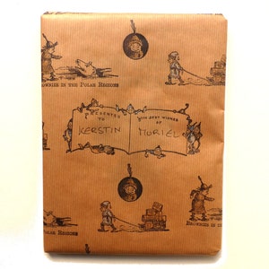 May include: Brown wrapping paper with a repeating pattern of small illustrations of people and objects. The paper has a handwritten inscription that reads "Presented to Kerstin with best wishes of Muriel".