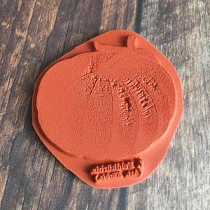 May include: A red rubber stamp with a detailed image of a pumpkin. The stamp is labeled "Red Pumpkin (c)Lori Art".