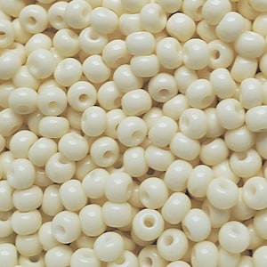 May include: A close-up view of a pile of small, round, white beads. The beads are smooth and have a hole in the center.