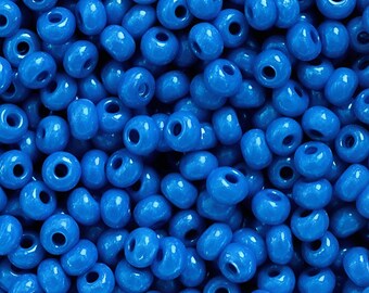 Puede incluir: Una gran colección de pequeñas cuentas de vidrio azul opaco, redondas y lisas. Cada cuenta presenta un acabado brillante y un orificio central para enhebrar. Las cuentas son uniformes en forma y tamaño, creando una superficie azul vibrante.
