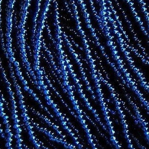 Op de afbeelding: Een close-up van een stapel donkerblauwe kralen. De kralen zijn klein en rond en hebben een metallic glans.