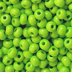 May include: A close-up image of a large quantity of lime green seed beads. The beads are round and have a smooth, glossy finish.