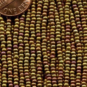 Puede incluir: Primer plano de una hebra de peque&ntilde;as cuentas doradas con un ligero brillo iridiscente. Las cuentas est&aacute;n dispuestas en filas y tienen aproximadamente el tama&ntilde;o de una moneda de un c&eacute;ntimo de euro.