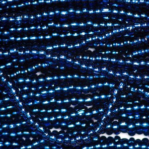 Op de afbeelding: Een close-up van een stapel donkerblauwe glazen kralen. De kralen zijn klein en rond en hebben een glanzende, metallic afwerking.