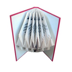 May include: An open book with pages folded into a triangular shape. The book has a red cover and white pages with black text. The pages are folded in a fan-like pattern, creating a unique visual effect.