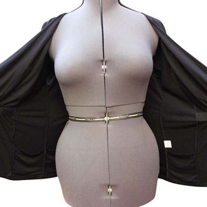 Puede incluir: Una chaqueta negra ligera con cierre de cremallera y dos bolsillos. La chaqueta est&aacute; desabrochada y colocada sobre un maniqu&iacute;.