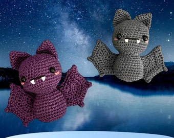May include: Two crocheted bats with big eyes and toothy grins, one purple and one gray, flying against a starry night sky background.