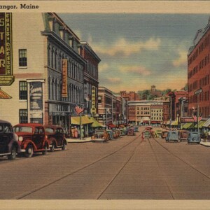 May include: Vintage postcard depicting Main Street in Bangor, Maine. The image shows a street lined with buildings, shops, and parked cars. The sky is overcast. The postcard has the text "Main Street, Bangor, Maine" at the top.
