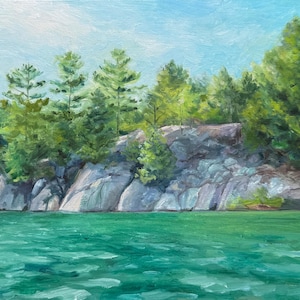 Puede incluir: Pintura al óleo de un paisaje sereno con un lago turquesa en primer plano. Rocas grises y exuberantes árboles verdes bordean la orilla bajo un cielo azul claro. La obra captura una escena natural tranquila.