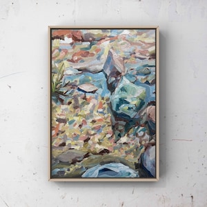 Puede incluir: Una pintura de un arroyo con rocas y guijarros en tonos de azul, verde, marrón y amarillo. El agua es de un azul claro y las rocas son de diversas formas y tamaños.