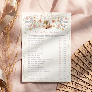 May include: A wedding shoe game card with floral illustrations and the title "The wedding shoe game." The card features a list of questions for the couple to answer during the game. A decorative fan is in the background.