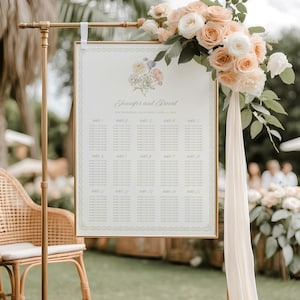 Può includere: Un tableau di nozze in metallo dorato con una composizione floreale. Il grafico mostra i nomi degli ospiti e i posti a sedere. Il testo recita "Jennifer and David" e "The San Francisco, California | April 15, 2023". Una sedia in vimini è in primo piano.
