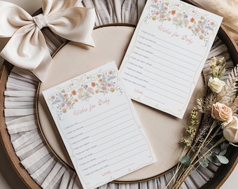 Può includere: Due biglietti a tema floreale con il testo " Wishes for Baby" e righe per scrivere messaggi. I biglietti sono su un vassoio di legno con un bordo di pizzo bianco e un fiocco bianco.
