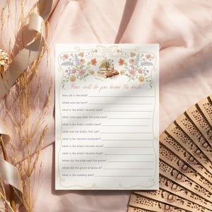 Może przedstawiać: Kremowa karta do gry na baby shower z ilustracjami kwiat&oacute;w i książek. Tekst "How well do you know the bride?" znajduje się na g&oacute;rze, z pytaniami do uzupełnienia poniżej. Dekoracyjny wachlarz w tle.