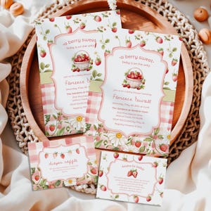 Może przedstawiać: Zaproszenia i kartki na baby shower z motywem truskawek. Zaproszenia przedstawiają kosz truskawek i tekst "a berry sweet baby is on the way". Kartki zawierają teksty na loterię pieluszkową i książki dla dziecka.