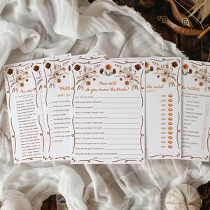 May include: A set of five bridal shower game cards with floral and botanical designs. The cards have a cream background with brown text and decorative borders. The games include "The Weds", "Why Do", "How well do you know the bride?", "She said", and "I'd rather".