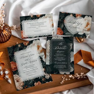 May include: Wedding stationery set with floral designs and white lace edging. The set includes invitation cards, a response card, and a thank you card. The floral pattern features white and orange peonies on a dark background.