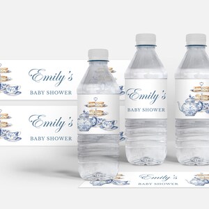 May include: Water bottle labels with a blue and white teapot, teacups, and pastries on a tiered stand. The labels say "Emily's Baby Shower".