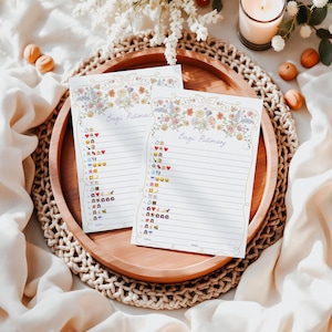 Peut inclure: Deux feuilles imprimables avec des bordures florales et le titre "Emoji Pictionary" en haut. Chaque feuille contient une liste d'emojis avec des num&eacute;ros &agrave; c&ocirc;t&eacute;.