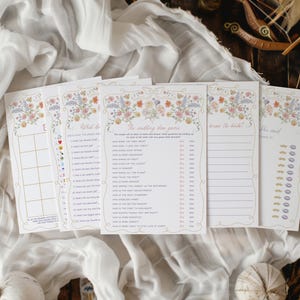 K&ouml;nnte beinhalten: Eine Sammlung von Spielkarten f&uuml;r eine Hochzeitsfeier mit floralen Designs. Die Karten zeigen verschiedene Spiele, darunter "The Wedding Shower Game" und "Know the Bride?". Die Karten sind auf wei&szlig;em Papier mit einem zarten floralen Rand gedruckt.