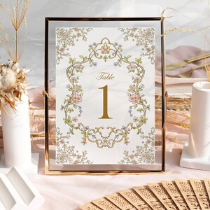 May include: A gold-framed table number card with a floral design and the text "Table 1" in gold lettering.