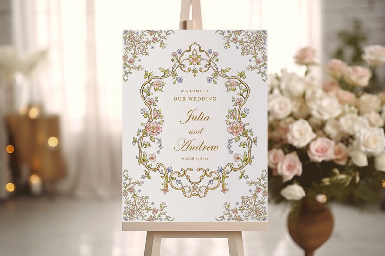 May include: A white wedding sign with a gold ornate frame and floral accents. The sign reads "Welcome to our wedding Julia and Andrew March 6, 2024".