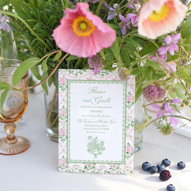 May include: A rectangular wedding invitation card with a white center and a decorative border featuring pink roses and green vines. The text reads: Florence and Gerald, INVITE YOU TO THEIR WEDDING, 10/10/2027, two o'clock in the afternoon, The Gardens at Heather Farm, 1540 Marchbanks Drive, Walnut Creek, CA 94598, RECEPTION TO FOLLOW.