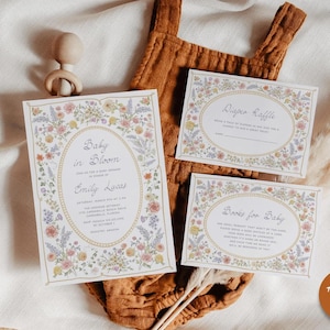May include: A floral-themed baby shower invitation with the text "Baby in Bloom" and the name "Emily Lucas". The invitation includes details about the date, time, and location of the shower. There are also two smaller cards with floral borders, one for a diaper raffle and one for a book request.
