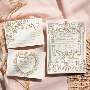 May include: Wedding stationery set featuring an invitation, RSVP card, and thank you card with floral and gold accents. The invitation reads "Meredith and David" and includes event details. A wooden fan is in the background.
