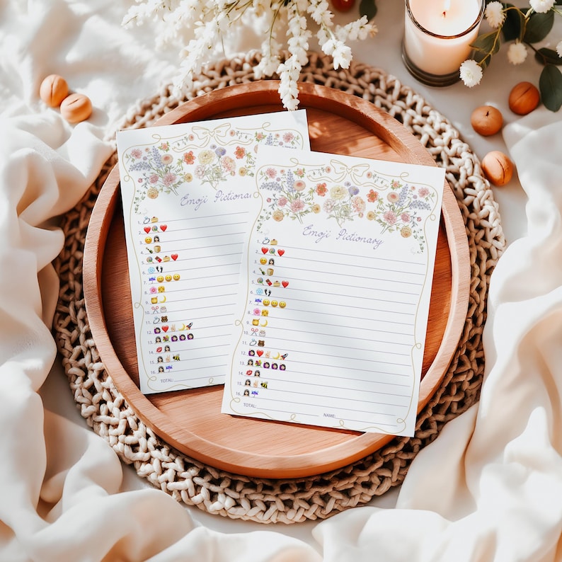 May include: Two printable sheets with floral borders and the title "Emoji Pictionary" at the top. Each sheet has a list of emojis with numbers next to them.