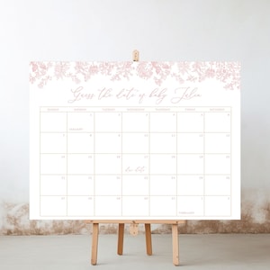 May include: A white calendar with a floral border in pink. The calendar is for the month of February and has the text "Guess the date of baby Julia" at the top.