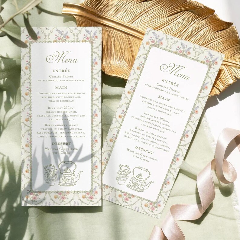 K&ouml;nnte beinhalten: Zwei Hochzeitsmen&uuml;karten mit floralen R&auml;ndern und eleganter Schrift. Die Men&uuml;s listen Vorspeisen, Hauptgerichte und Dessertoptionen auf. Ein goldenes Blatt und ein rosa Band sind im Hintergrund.