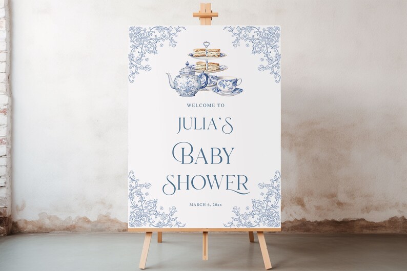 May include: A white sign with blue floral borders and a blue and white teapot, teacup, and tiered cake stand with a welcome to Julia's Baby Shower sign and the date March 6, 20xx.