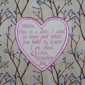 Puede incluir: Un parche en forma de corazón rosa con bordado blanco. El texto dice: "Hattie, Esta es una camisa que usé para vestir y cuando la tengas en tus manos, debes saber que estoy ahí. Con amor, Abuelo Jim."