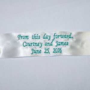 Può includere: Nastro di raso bianco con ricamo blu turchese che recita "From this day forward. Courtney and James June 25, 2016."