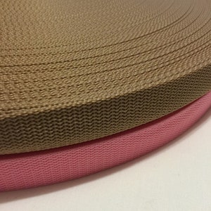 Puede incluir: Dos rollos de cinta, uno marr&oacute;n y otro rosa. La cinta marr&oacute;n est&aacute; encima de la cinta rosa.