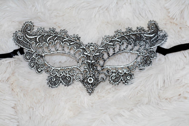 May include: A black lace masquerade mask with silver accents. The mask has a delicate, intricate design and is perfect for a costume party or a night out.