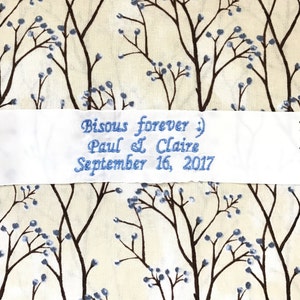 Può includere: Nastro di raso bianco con testo ricamato in blu che recita "Bisous forever :) Paul & Claire September 16, 2017".