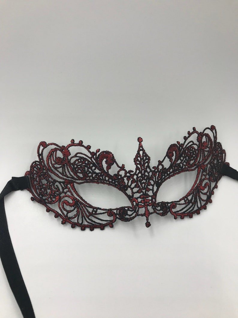May include: A red and black lace masquerade mask with black ribbon ties.