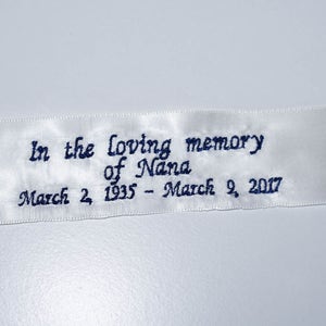 Può includere: Nastro di raso bianco con testo ricamato in blu: "In memoria affettuosa di Nana 2 marzo 1935 - 9 marzo 2017"