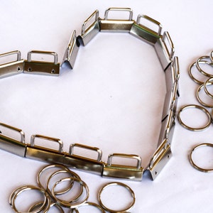 May include: A silver metal heart-shaped frame made of interlocking pieces with a set of silver key rings.