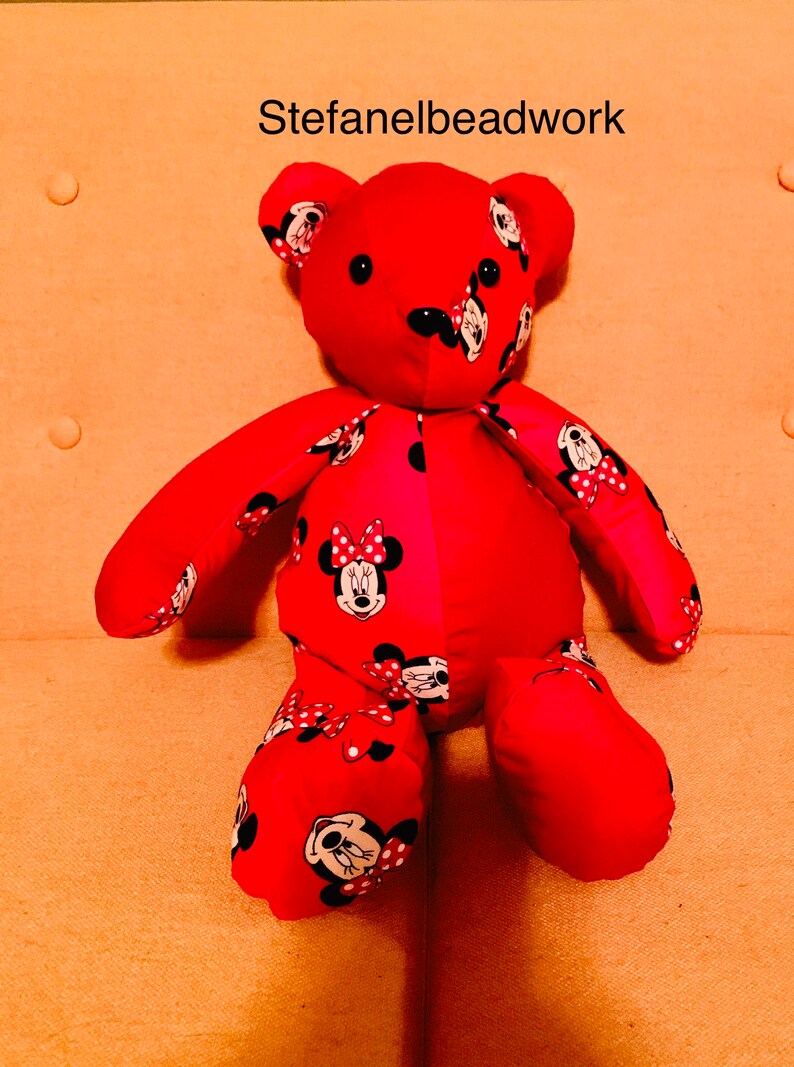 Op de afbeelding: Rode pluche teddybeer met een Minnie Mouse print. De beer zit op een licht oranje bank. De tekst "Stefanelbeadwork" is zichtbaar in het midden bovenaan de afbeelding.
