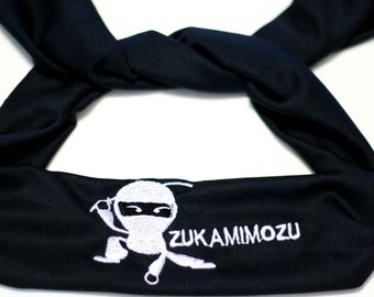 Puede incluir: Diadema negra con un diseño de ninja bordado en blanco y el texto "ZUKAMIMOZU".