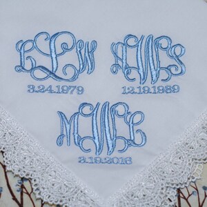 May include: White handkerchief with blue embroidered monograms and dates. The monograms are "LW", "AWS", and "MWE". The dates are "3.24.1979", "12.19.1989", and "3.19.2016".