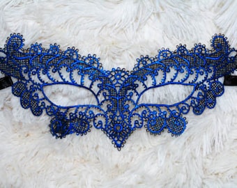 May include: A blue lace masquerade mask with black ribbon ties. The mask has a delicate, intricate design.